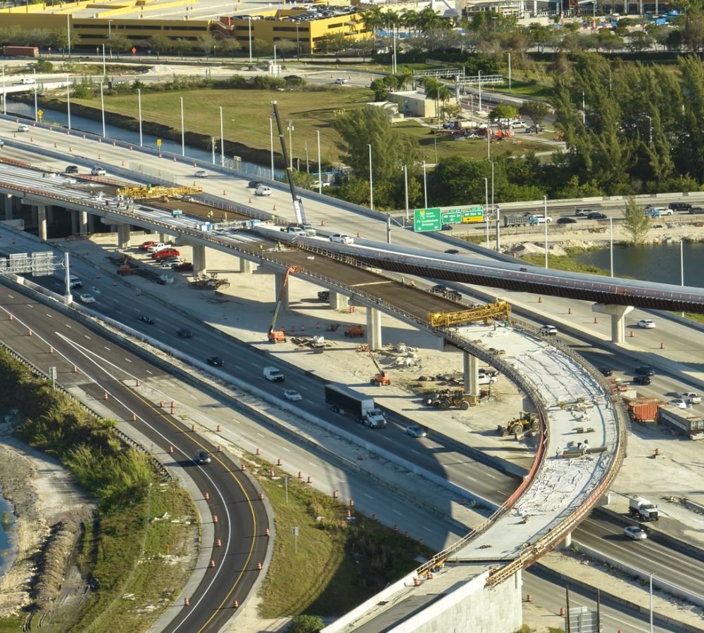 Construction roadworks on american transport infrastructure. Renovation of highway road interchange with moving traffic in Miami, Florida. Development of interstate transportation concept.