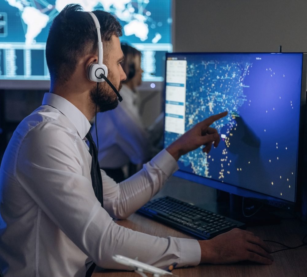 In headphones. People are working by computers in airline company.