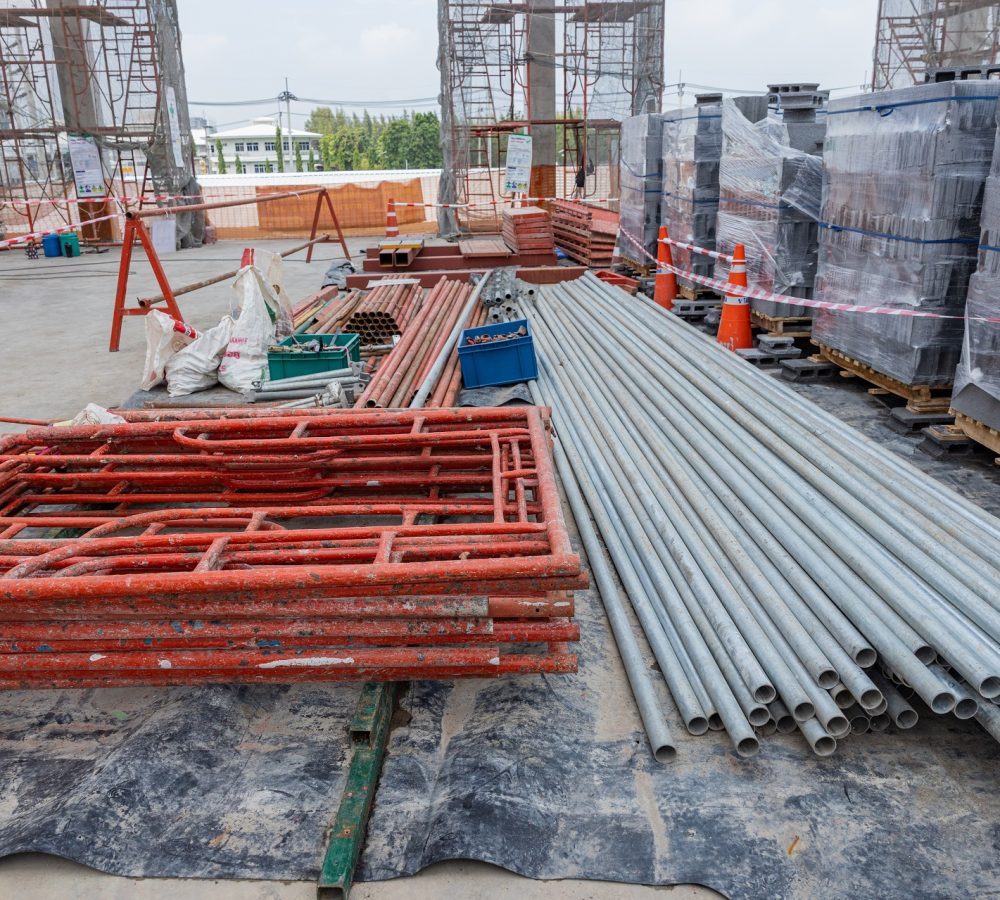 Stacked Metal Scaffolding Pipes at Construction Site Neatly stacked metal scaffolding pipes and platforms at a construction site, prepared for use in structural framework assembly.